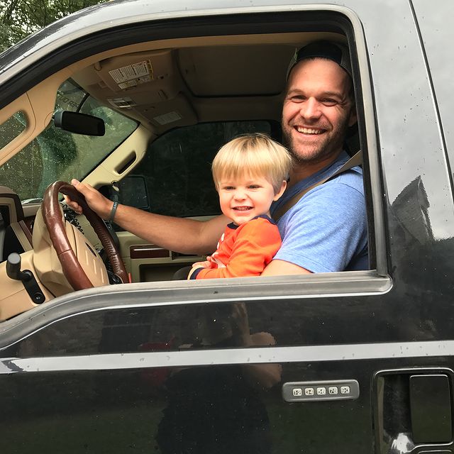 Matt Flynn smiling with his son in his car.